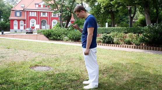 Andr&eacute; Johne, Praktikant in der Physiotherapie der HELIOS Klinik Bleicherode, simuliert die ungesunde Handyhaltung beim Blick auf sein Smartphone. (Foto: J. Weller)