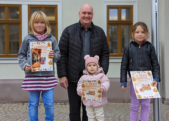 B&uuml;rgermeister Steffen Grimm gratulierte den Gewinnerinnen Magda Urban (rechts), Paulina Schubert (vorne Mitte) und Daphne Langhammer (links) des diesj&auml;hrigen K&uuml;rbisschnitzwettbewerbes (Foto: Janine Skara)