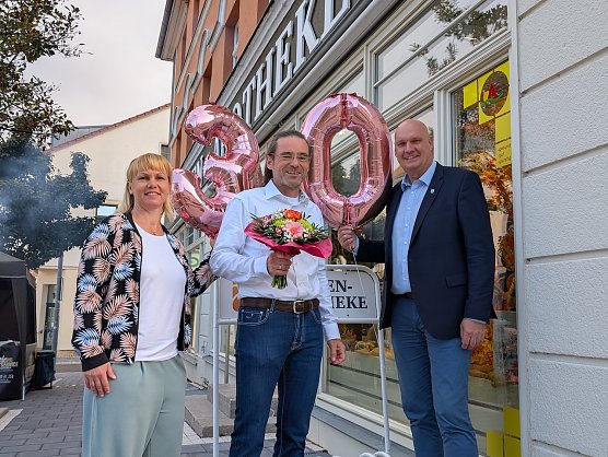Citymanagerin Kathrin Kilian (li.) und B&uuml;rgermeister Steffen Grimm (re.) gratulierten Thomas Wi&szlig;gott zum 30. Geburtstag der Loewen-Apotheke. (Foto: Janine Skara)