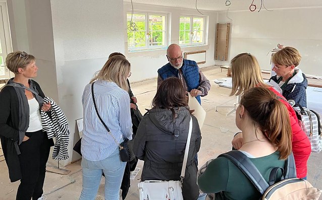 Bild: Thomas K&uuml;hn (Mitte), Fachgebietsleiter Hochbau/Geb&auml;ude- u. Energiemanagement der Stadtverwaltung, zeigt den Elternvertretern die Pl&auml;ne f&uuml;r die Innenraumgestaltung der Kita K&auml;the Kollwitz.
