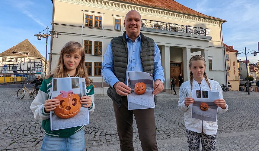 B&uuml;rgermeister Steffen Grimm mit zwei Gewinnerinnen des K&uuml;rbisschnitzwettbewerbs